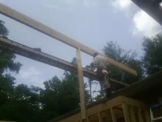 Carpenter setting a ridge beam over a new addition frame — Ice Dam Removal by Roofing Brothers in Bonham