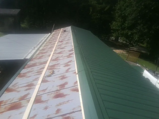Old rusted panels beside newly installed green metal roofing — Wind Damage Roof Repair by Roofing Brothers in Bonham