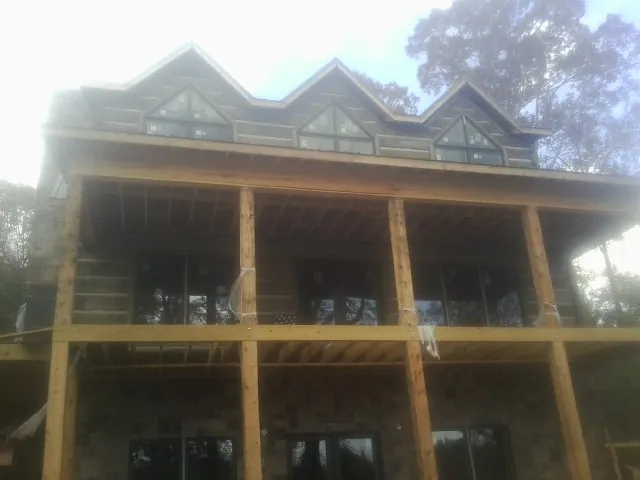 Dormers and porch framing on a large log home under construction — Roof Coating work by our crew in Bonham