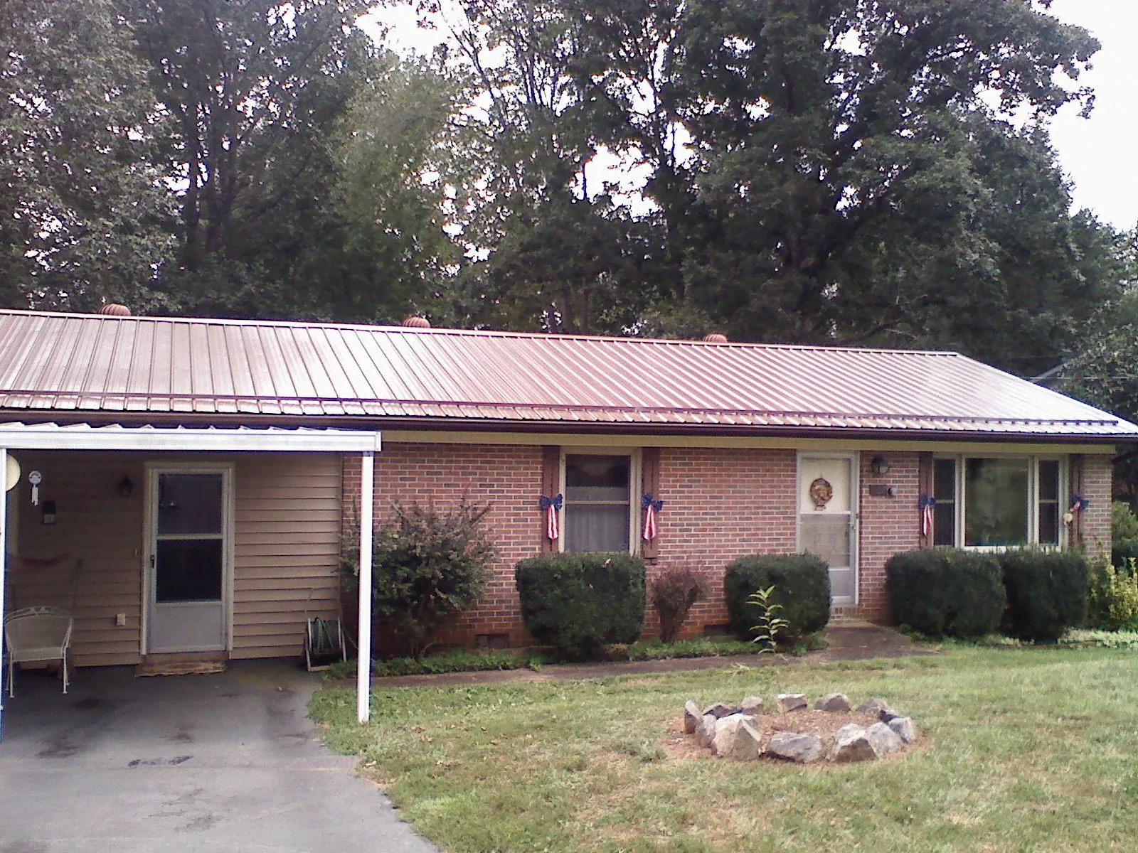 Bronze metal roof and carport on a brick ranch home — Roof Repair work by our crew in Bonham